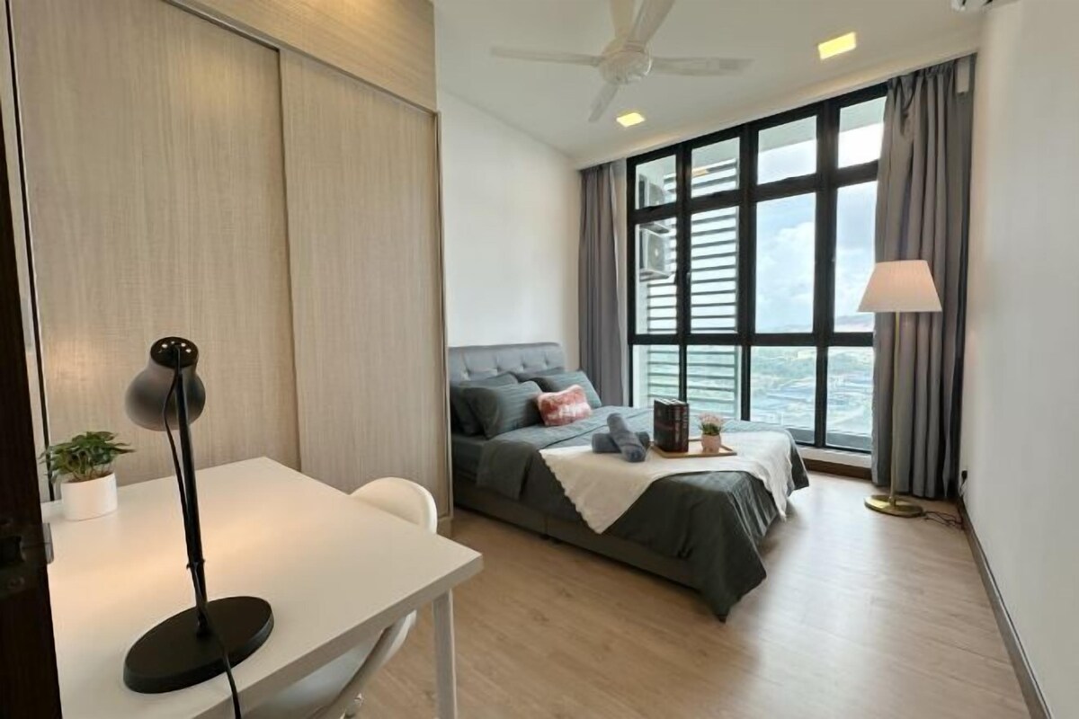 A modern bedroom with a bed, a desk, a chair, a lamp, and a window with curtains.