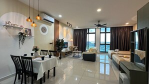 A modern living room with a dining area, a sofa set, a TV, and a large window with curtains. - Green Haven (Masai)