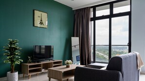 A modern living room with a television, a sofa, a coffee table, and a large window with a view. - Green Haven (Masai)