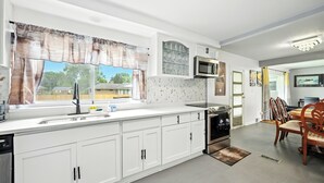 A modern kitchen with white cabinetry, a built-in microwave, and a large window with curtains. - Spacious 5-bedroom house with Jacuzzi, Game room & WIFI in delightful Southfield (Southfield)