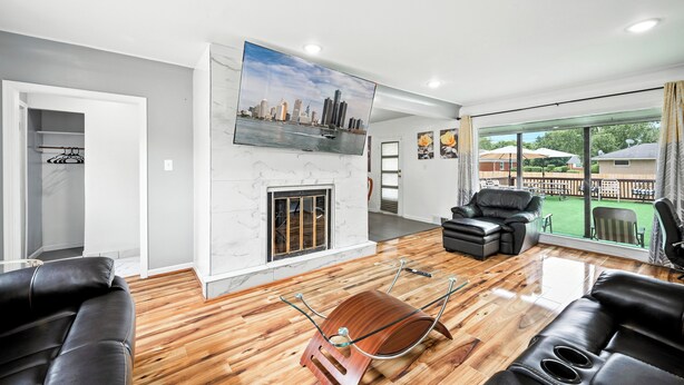 A modern living room with a cityscape painting, a fireplace, leather sofas, and a view of the outdoors. - Spacious 5-bedroom house with Jacuzzi, Game room & WIFI in delightful Southfield (Southfield)