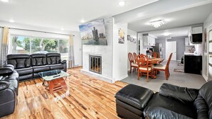 A modern living room with a fireplace, a dining area, and a kitchen. - Spacious 5-bedroom house with Jacuzzi, Game room & WIFI in delightful Southfield (Southfield)