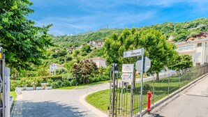 A paved road leading to a gated entrance with a sign indicating 'via Ottumo'.