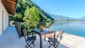 A balcony with a table and chairs, overlooking a lake and mountains. - Apartment Svasso by Interhome (Lago di Mezzola)
