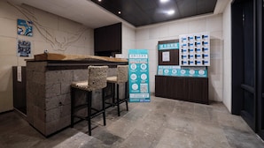 A self-check-in area with a counter, seating, and self-check-in kiosks. - ZZZ HOTEL (Jiaoxi)