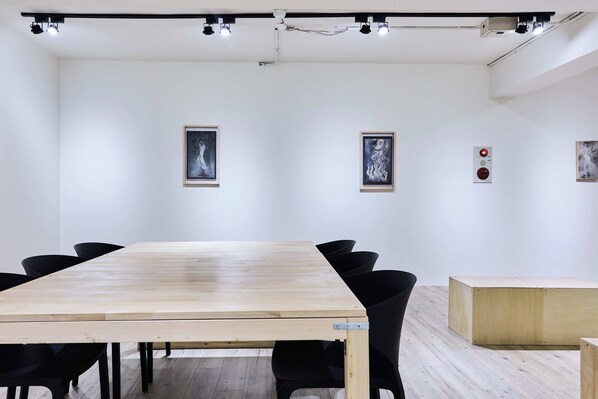 A conference room with a long table, black chairs, and framed artwork on the walls. - ZZZ HOTEL (Jiaoxi)