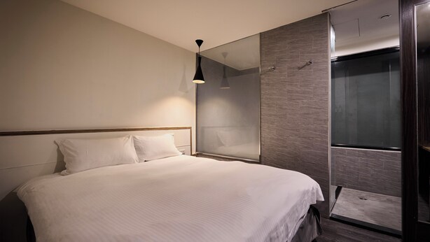 A modern bedroom with a large bed, a glass shower enclosure, and a pendant light. - ZZZ HOTEL (Jiaoxi)