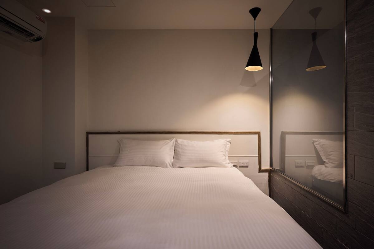 A neatly made bed with white linens in a modern hotel room.