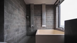 A modern bathroom with a bathtub, shower, and a window providing natural light. - ZZZ HOTEL (Jiaoxi)