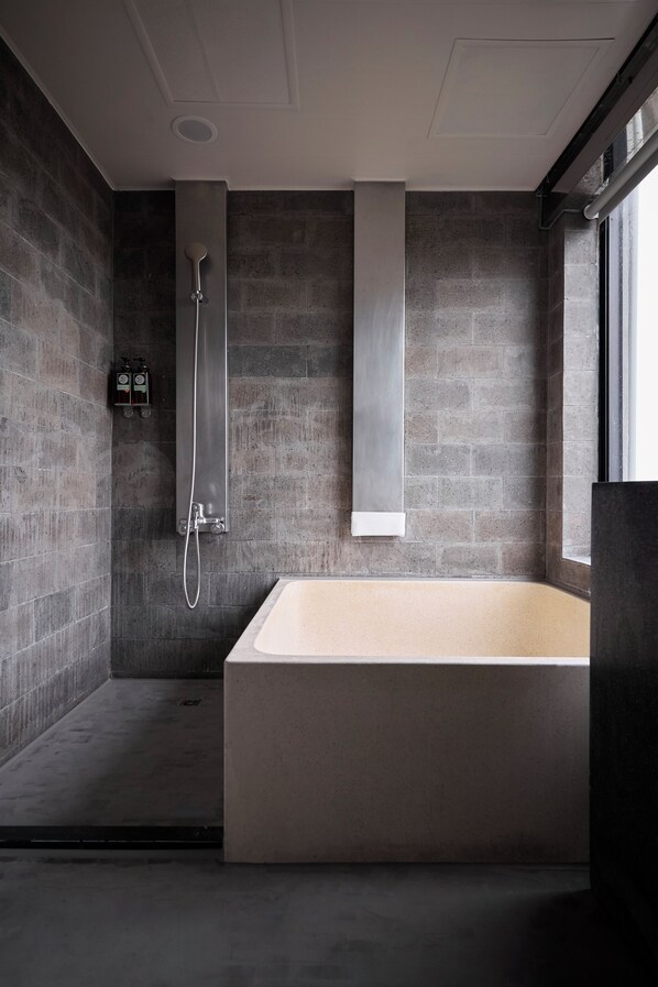 A modern bathroom with a large bathtub, a shower, and a window providing natural light. - ZZZ HOTEL (Jiaoxi)
