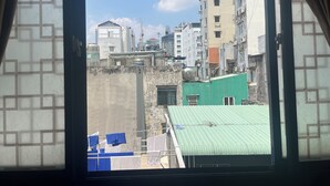 Vista attraverso una finestra su una zona urbana densamente popolata, con diversi edifici, sia residenziali che commerciali.