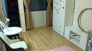 Una camera compatta con un letto, una scrivania con sedia, un armadio e una finestra con tende.