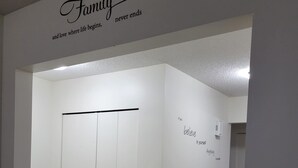 Un couloir avec une armoire blanche, un mur orné d’une affiche sur le thème de la famille et un court message.