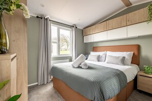Een moderne slaapkamer met een groot bed, een houten hoofdbord en ingebouwde opbergkasten.