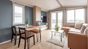 A modern living room with a dining area, a sofa set, and a TV.