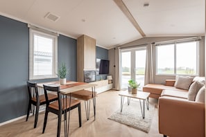 Een moderne woonkamer met een eethoek, een zithoek en een televisie.