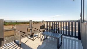A deck with outdoor seating and a view of the landscape.