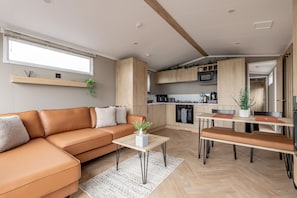 Eine moderne Küche mit Holzschränken, einem Esstisch mit Bänken und einer eingebauten Mikrowelle.