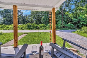 An outdoor seating area with a pergola, a wine bottle, and two glasses on a table. - Bear Walk Cottage in Black Mountain (Black Mountain)