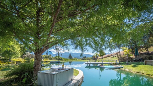 Un área de piscina exterior tranquila con un jacuzzi integrado, rodeada de exuberante vegetación y vistas despejadas a montañas al fondo.