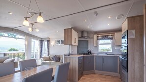 Una cocina moderna con zona de comedor, armarios de madera y vistas al exterior.