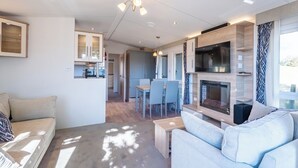 Una sala de estar moderna con un sofá, una chimenea y un comedor con mesa y sillas.