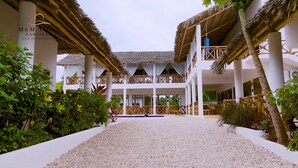 Ein Resort mit Innenhof, weißen Säulen und strohgedeckten Gebäuden.