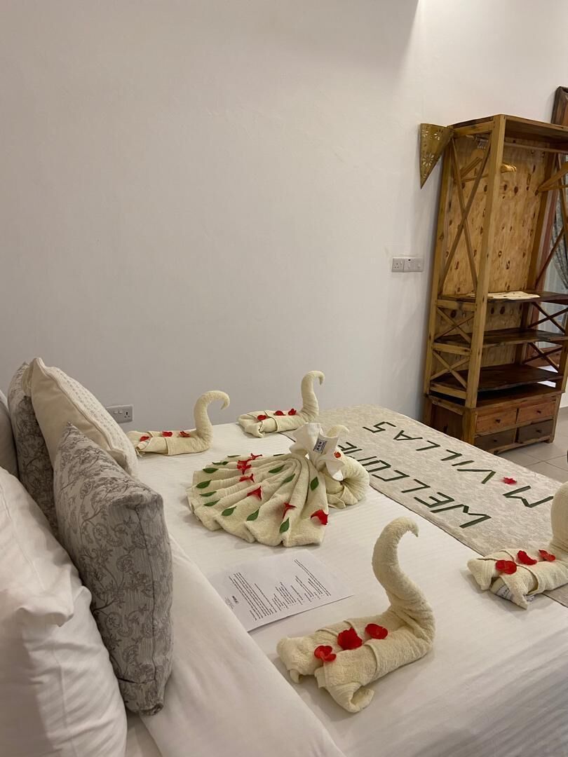 Una cama bien hecha con toallas decorativas y un tapete de bienvenida.