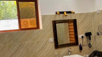 A bathroom with a toilet, sink, mirror, window, and a wall-mounted heater.