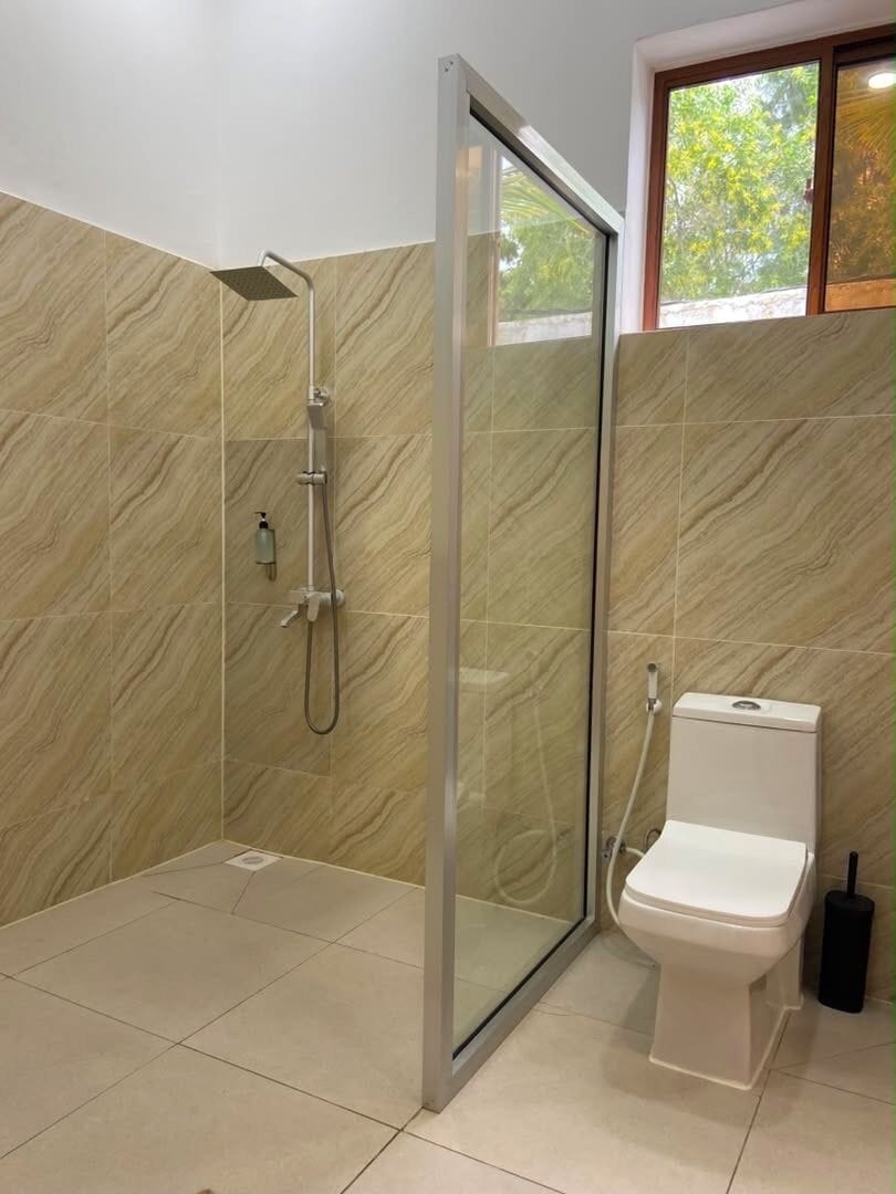 Ein Badezimmer mit Dusche, Toilette und Glastür.