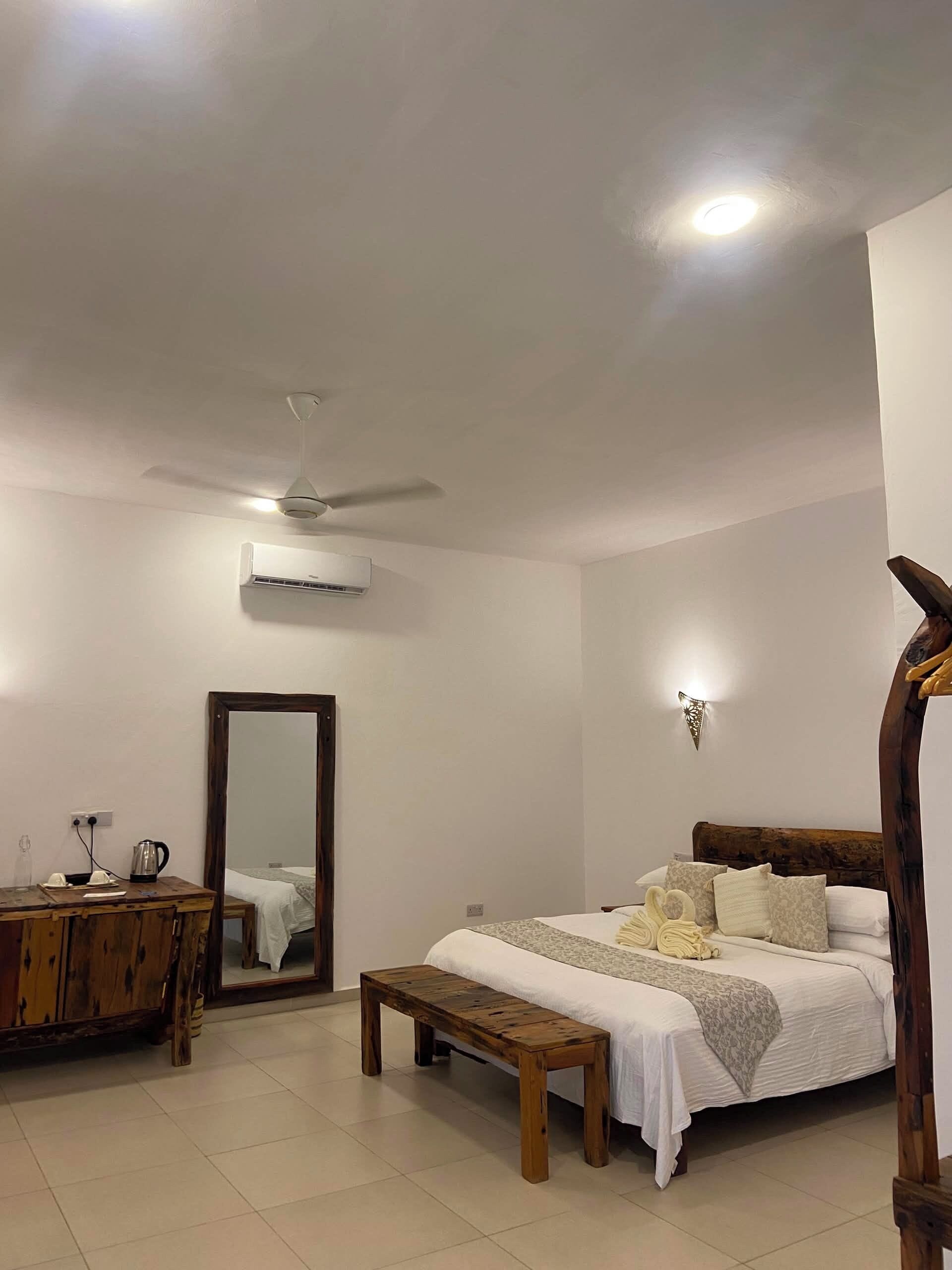 A bedroom with a bed, bedside table, mirror, and ceiling fan.