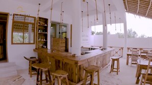 Eine Bar mit Holzsitzmöbeln und einem Schild mit der Aufschrift 'M&M Villas Zanzibar'.