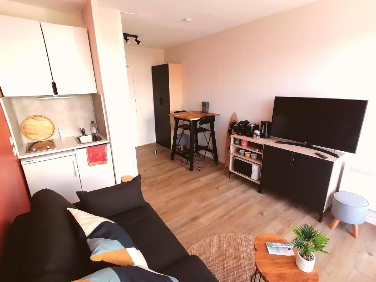 Ein gemütlicher Wohnbereich mit Sofa, Esstisch, Fernseher und einer Küchenzeile.