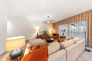 A modern living room with a sofa, a coffee table, a lamp, and a TV.
