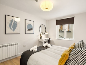 A hotel room with a bed, a desk, a chair, a window with a view, and artwork on the walls. - The Town Place @ Clifden Boutique Apartments (Clifden)