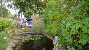 A pond with rocks and a statue, surrounded by lush greenery. - Schönow Forest Apartment (Berlin-Schönow)