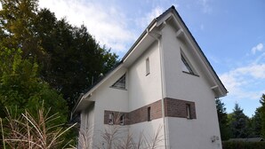 A modern two-story house with a white exterior and brown accents, surrounded by greenery. - Schönow Forest Apartment (Berlin-Schönow)