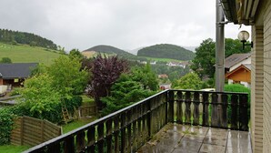 A balcony with a view of a rural landscape, including hills and houses. - Wohnung am Diemelsee bei WillingenWinterberg (Diemelsee)
