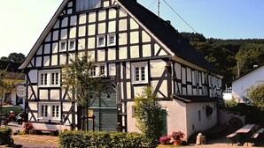 Un bâtiment traditionnel à colombages, doté d’un toit à forte pente, de nombreuses fenêtres et d’une porte verte.