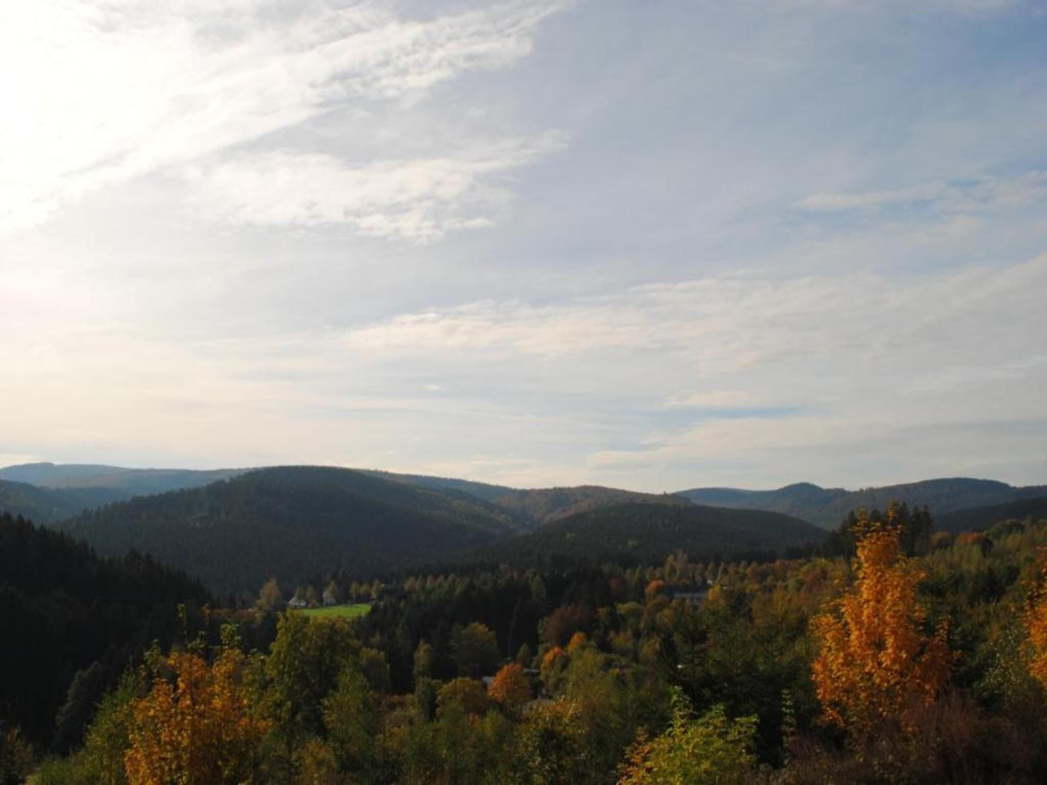 A panoramic view of a mountainous landscape with autumn foliage.