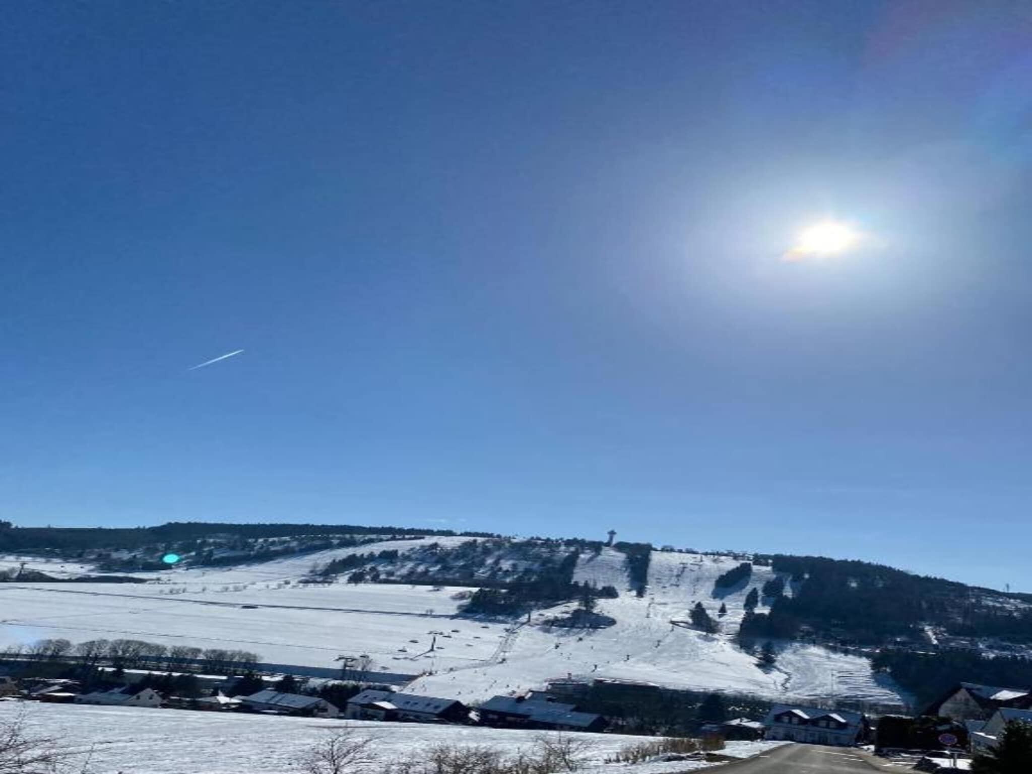 A snowy landscape with a clear sky and a distant mountain.
