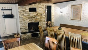 Ein gemütlicher Essbereich mit Kamin aus Stein, Holzstühlen und einem Tisch.