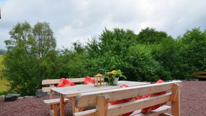 A wooden picnic table with benches, a lantern, and a potted plant with flowers. - Gemütlicher Rückzugsort in Olsberg-Elpe (Elpe)