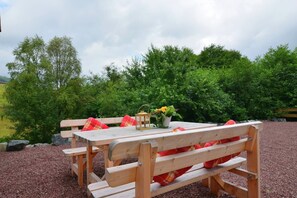 Une table de pique-nique en bois avec des bancs, une lanterne et une plante en pot.