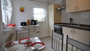 A compact kitchen with a dining area, featuring a window with a view, a coffee machine, and a stove. - Gemütlicher Rückzugsort in Olsberg-Elpe (Elpe)