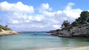 A beach with clear turquoise water, a sandy shore, and rocky cliffs. - Villa Sur A bit closer to heaven (Binisafua)