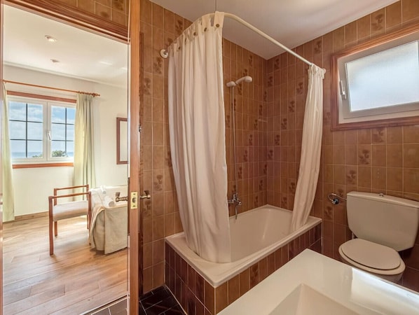 A bathroom with a bathtub, toilet, and shower curtain.
