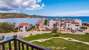 A coastal property with white buildings and red roofs, a parking area, and a view of the sea and hills. - Apt. Alcor, simply Mediterranean (Platges de Fornells)
