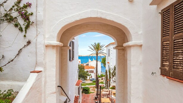 A narrow white-walled corridor with a tiled floor leading to a courtyard. - Apt. Alcor, simply Mediterranean (Platges de Fornells)
