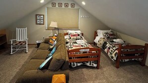 A small attic bedroom with two single beds, a rocking chair, and a couch.